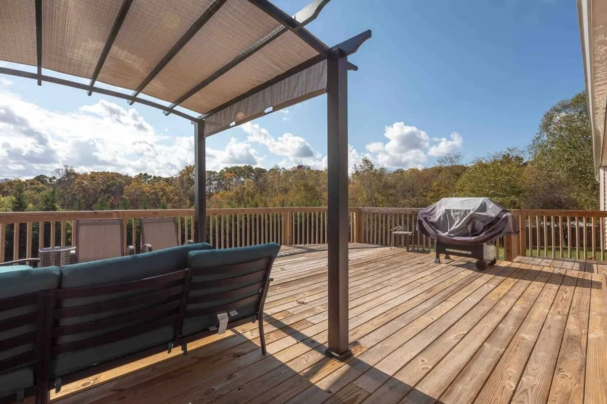 A close-up of the deck seating area featuring a modern grill and a canopy structure, surrounded by lush natural scenery. The setup invites guests to enjoy barbecues, relaxed meals, and time with loved ones outdoors, reflecting a laid-back and communal atmosphere.