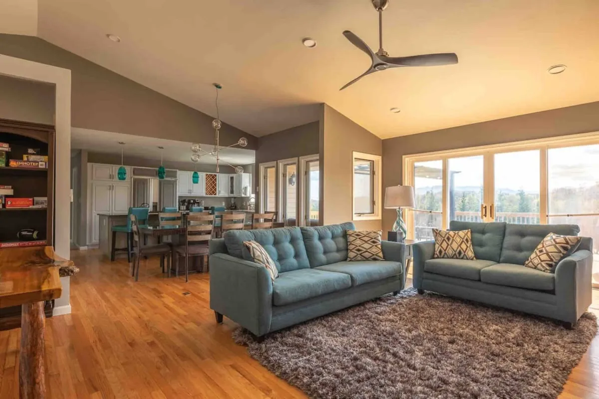 A spacious, light-filled area with sofas, a dining area, and large windows that let in natural light. The setting is perfect for both group activities and quiet moments, and the view outside connects the interior to the natural surroundings.