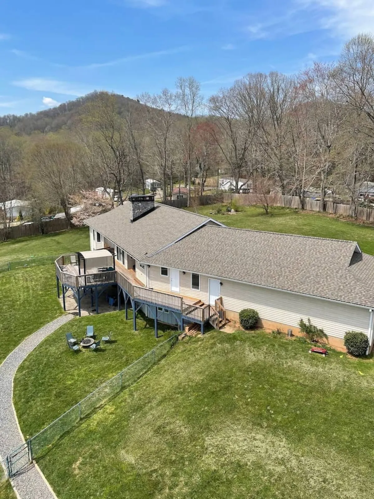The image showcases a beautiful, spacious mountain home nestled in lush greenery, with a generous deck perfect for gatherings, a crackling fire pit ideal for evening relaxation, and panoramic views of the surrounding mountains. The inviting outdoor spaces highlight opportunities for enjoying sunsets, stargazing, and connecting with nature, all within a tranquil, private setting.