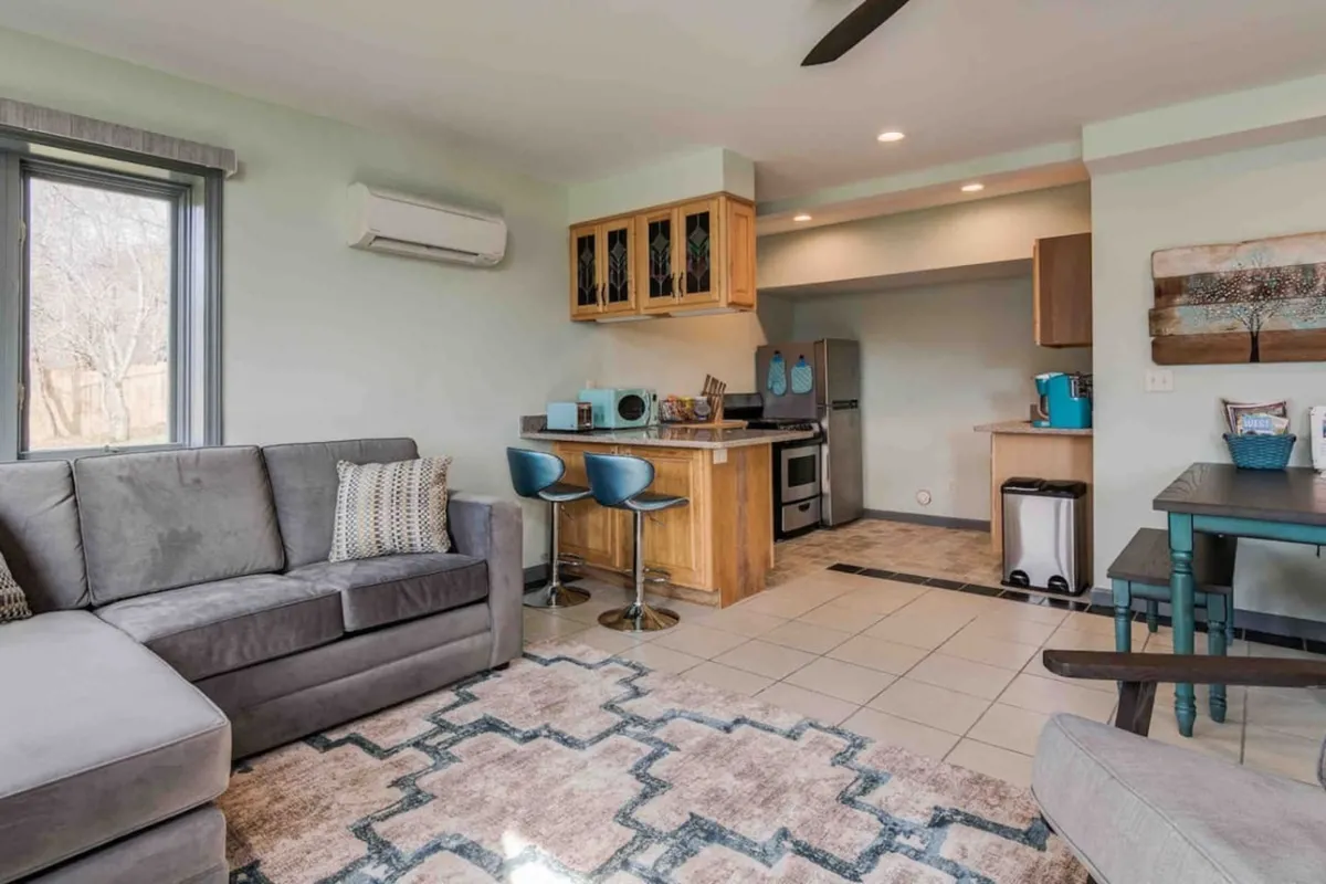 An open-concept living area with a comfortable sofa, a prominent kitchen island, and a dining table positioned to encourage conversation and group interaction. The space feels relaxed yet functional, providing different spots for cooking, dining, and socializing in close proximity.