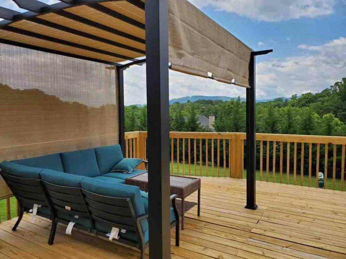 This image captures a spacious wooden deck with a comfortable outdoor seating area under a canopy, set against a picturesque mountain view. The scene exudes a tranquil and inviting mood, ideal for morning coffee, evening gatherings, and taking in the natural surroundings. The deck is designed for relaxation and small group activities, perfectly aligning with the section's emphasis on indoor/outdoor living.