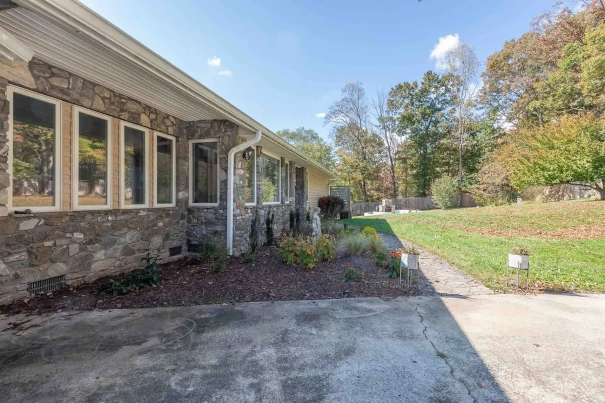 A striking exterior shot featuring the home’s elegant stone façade, large windows, and a landscaped garden. The inviting patio provides a peaceful spot to enjoy morning coffee while taking in the surrounding natural beauty, blending indoor comfort with outdoor serenity.