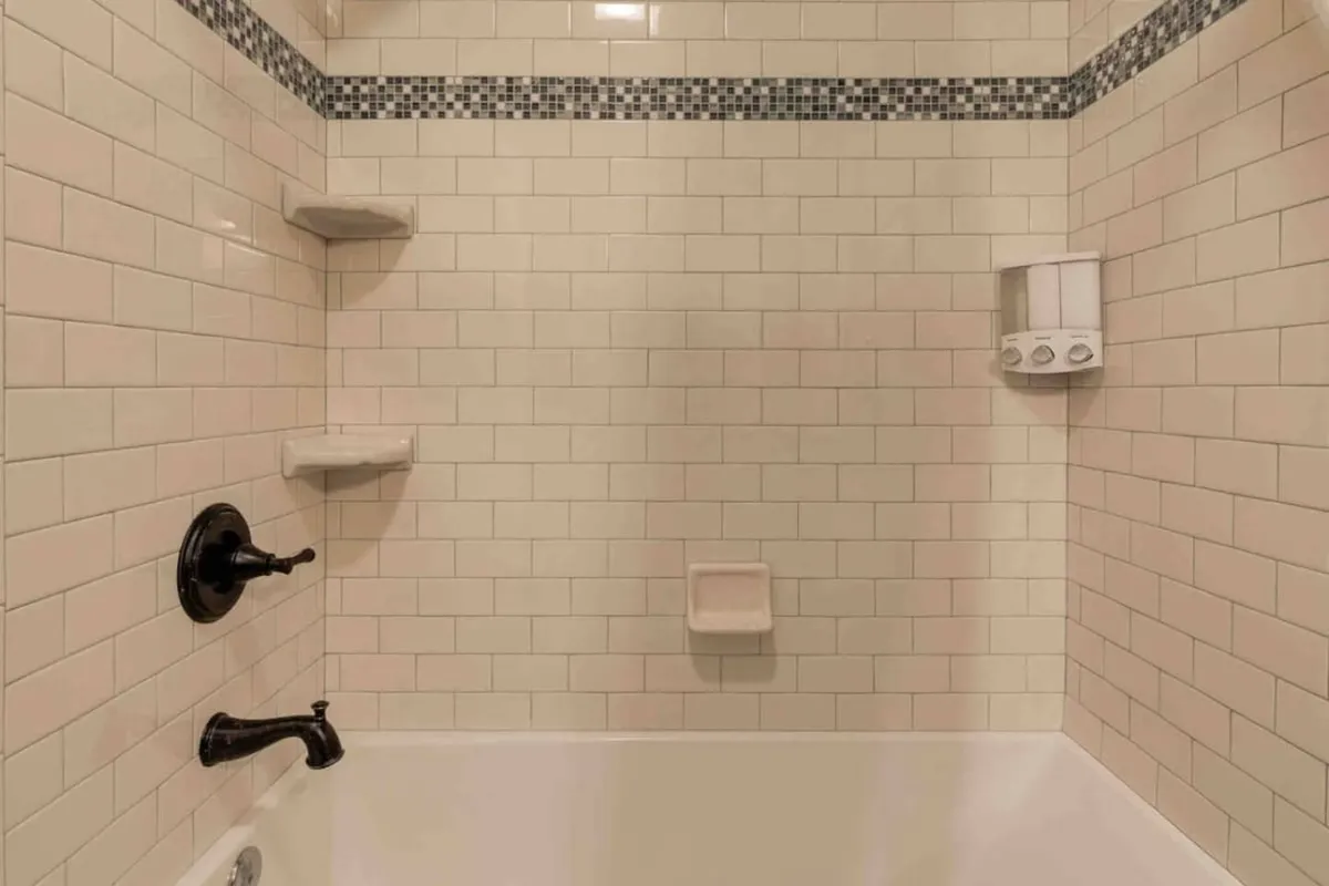 A contemporary bathroom with a sleek two-person bathtub, elegant tile work, and a modern shower head. The scene conveys serenity and the promise of soothing baths in a peaceful, upscale environment.